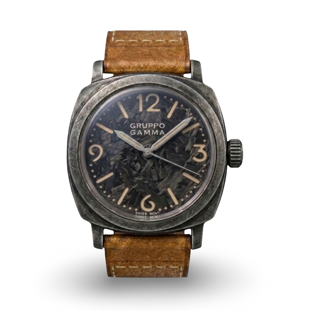 A Gruppo Gamma wristwatch with a distressed dark gray metal case, a black dial with beige Arabic numerals, and a brown leather strap, shown against a plain white background.