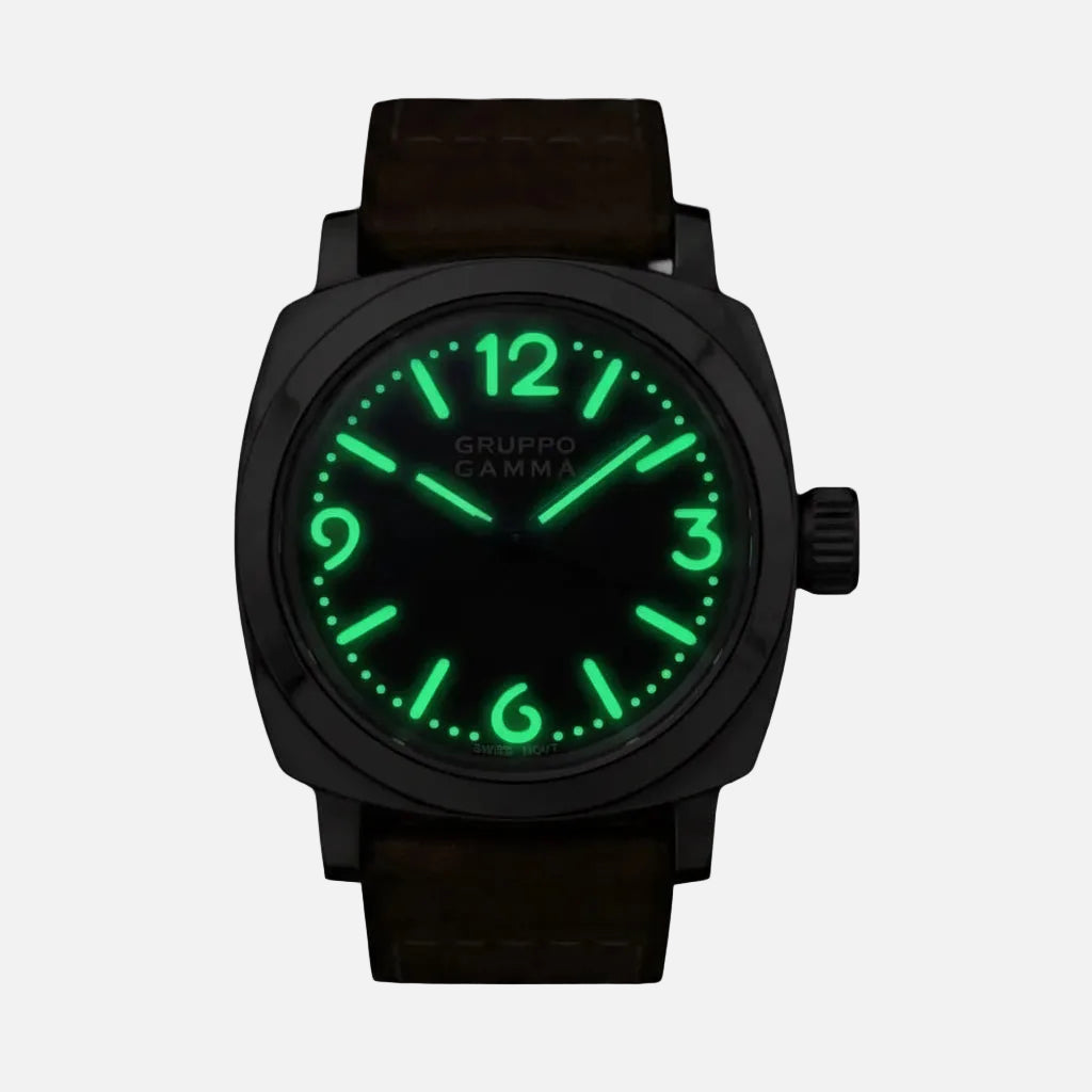 A wristwatch with a dark gunmetal-toned case, brown leather strap, and a glowing green luminescent dial and hour markers, shown against a solid black background.