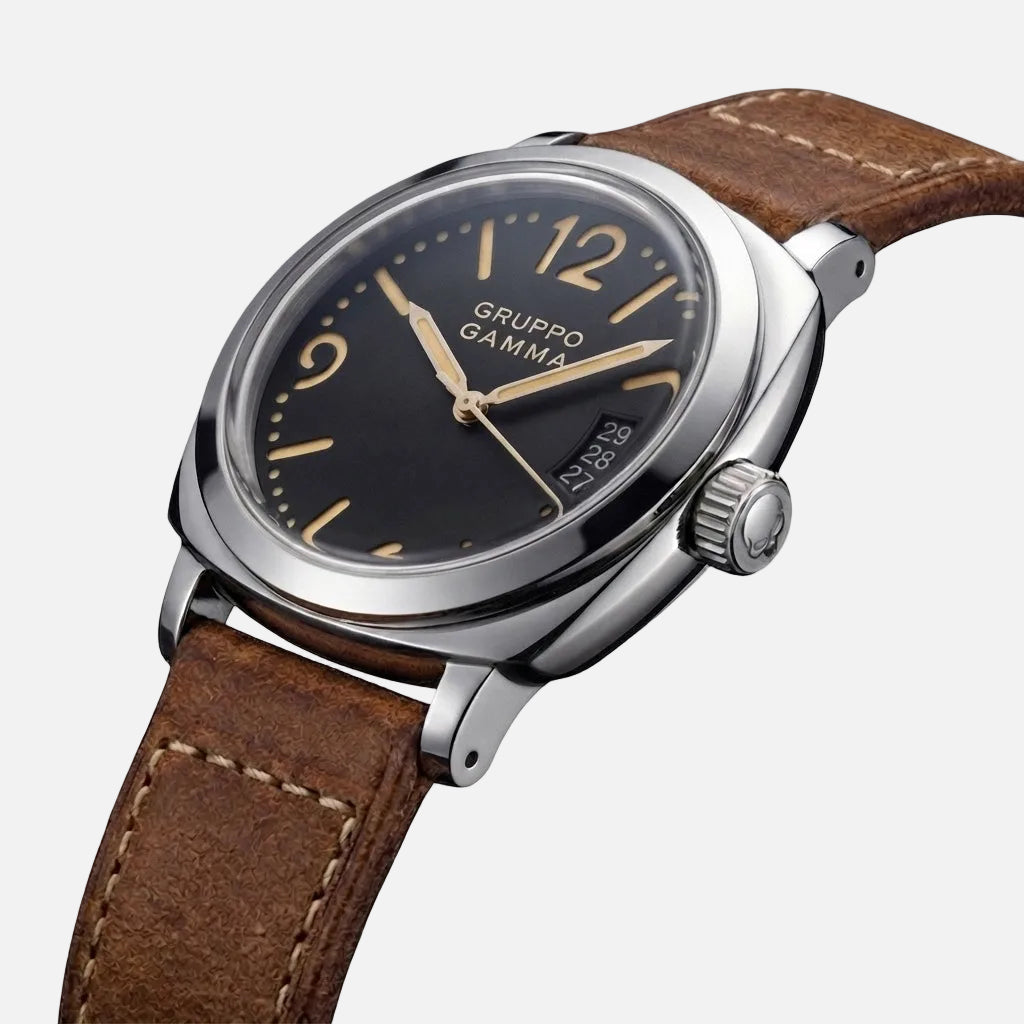 Grupo Gamma wristwatch with a black dial, silver-tone stainless steel case, and a brown leather strap, shown on a clean white background.