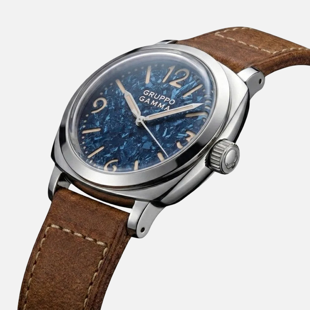 A Gruppo Gamma wristwatch featuring a textured blue dial, silver-tone stainless steel case, and a brown leather strap with white stitching, shown on a plain white background.