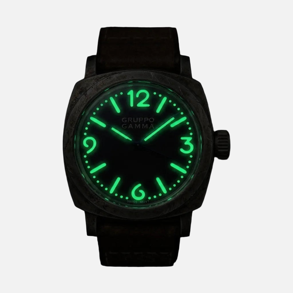 A Gruppo Gamma wristwatch with a dark textured case and a glowing green luminescent dial and numerals, shown against a solid black background.