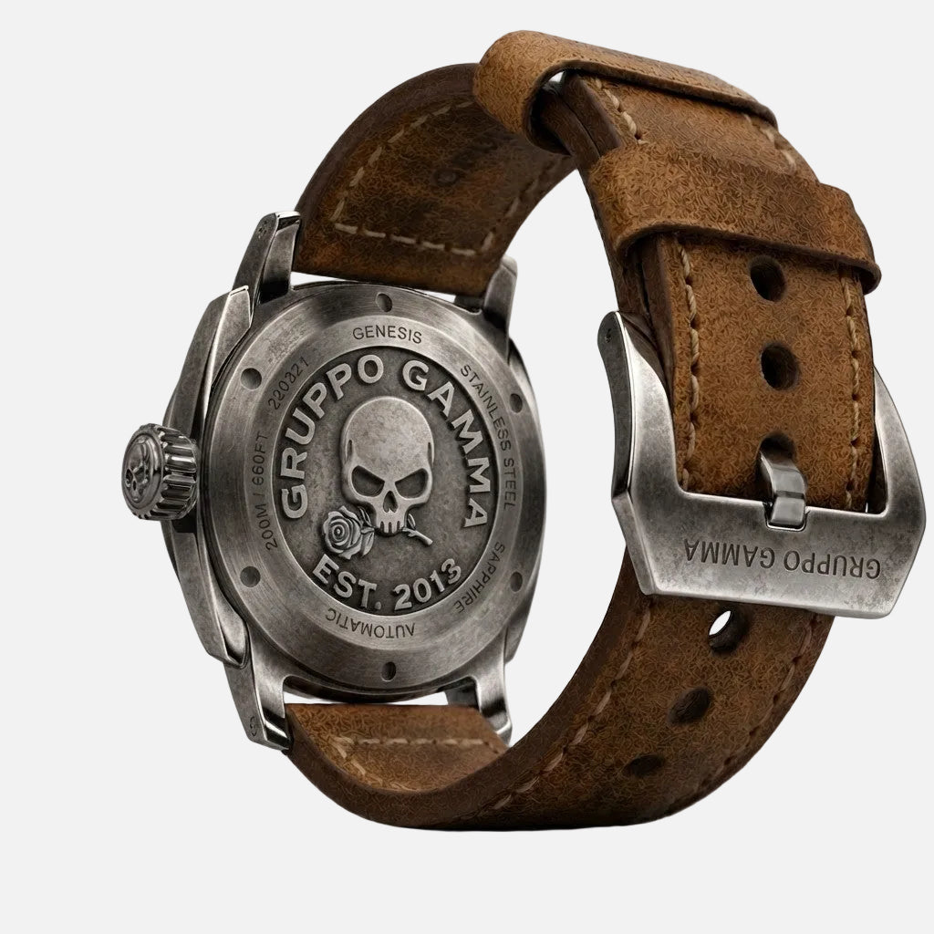 A close-up shot of the back of a Gruppo Gamma wristwatch with a brown leather strap and a polished silver-tone stainless steel case. The back of the case features an engraved skull and rose logo with the brand name 'GRUPPO GAMMA' and 'EST.